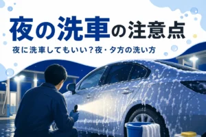 夜の洗車場の照明の下で、ライトを当てて車のボディを確かめている人の後ろ姿